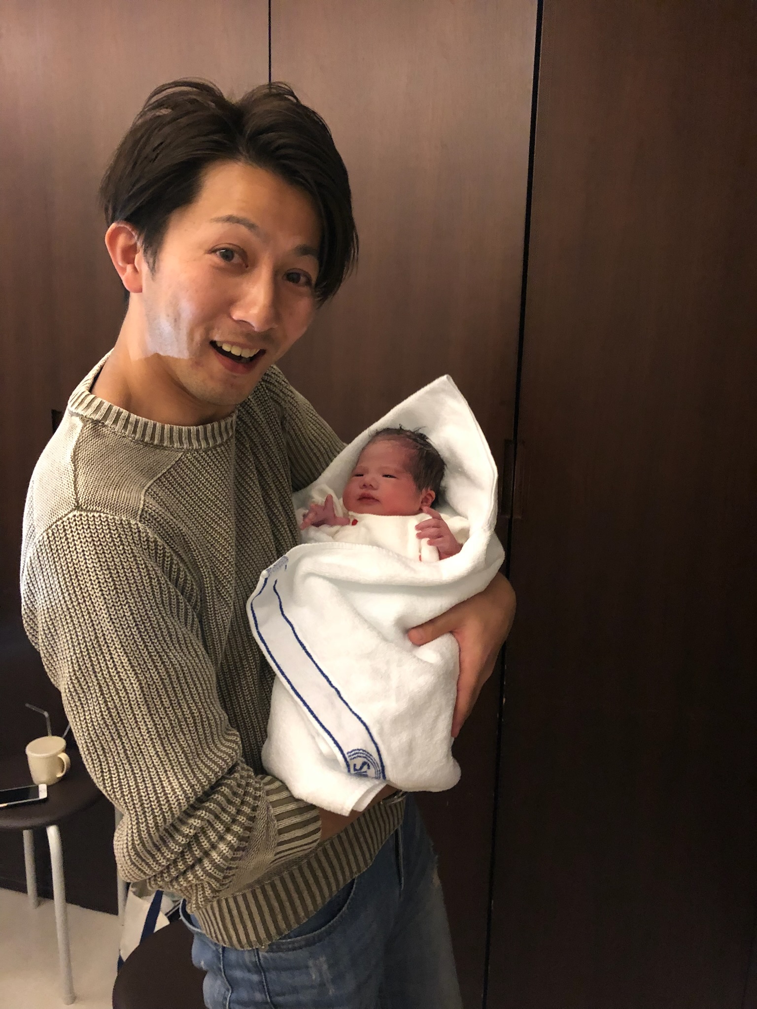 生まれたばかりの息子を抱く石井