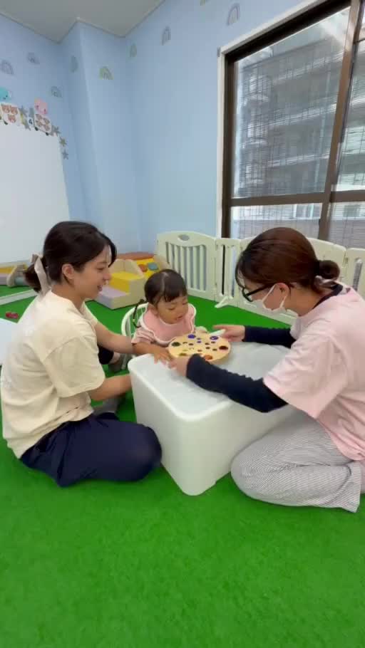スタッフと子どもたちが机を囲み、教材で一緒に遊ぶ様子